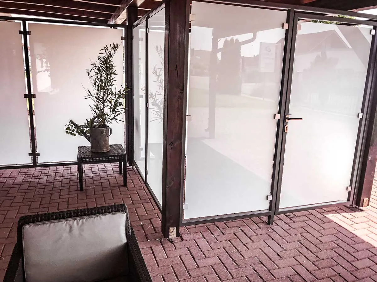 Windschutz aus Milchglas mit Stahlrahmen an der Terrasse