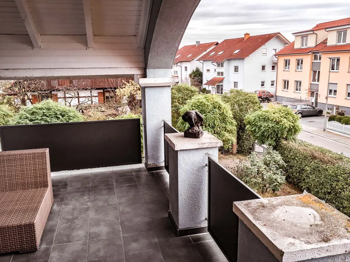 Balkongeländer mit dunkler Blechfüllung an überdachter Terrasse