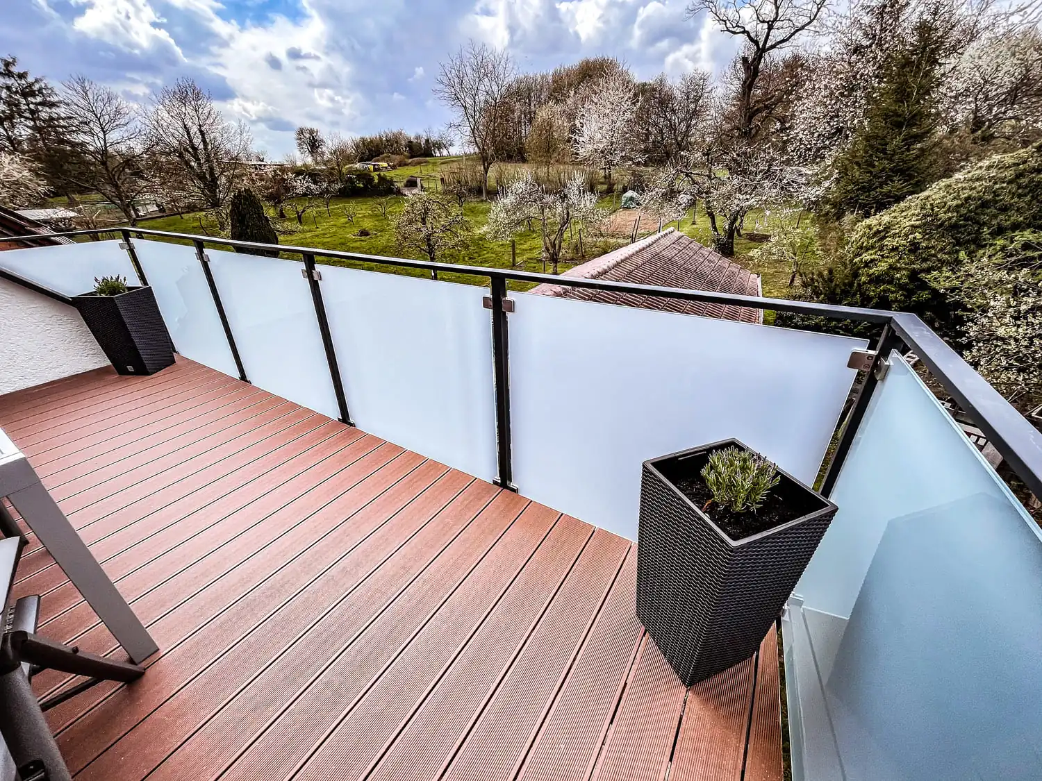 Balkongeländer aus Edelstahl mit Milchglasfüllung an Holzterrasse