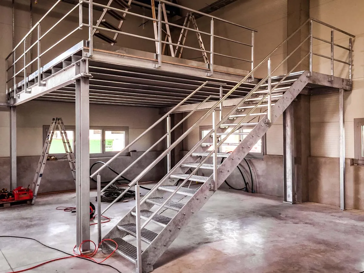 Verzinkte Stahlbühne mit Gitterrost und Treppe in Gewerbehalle