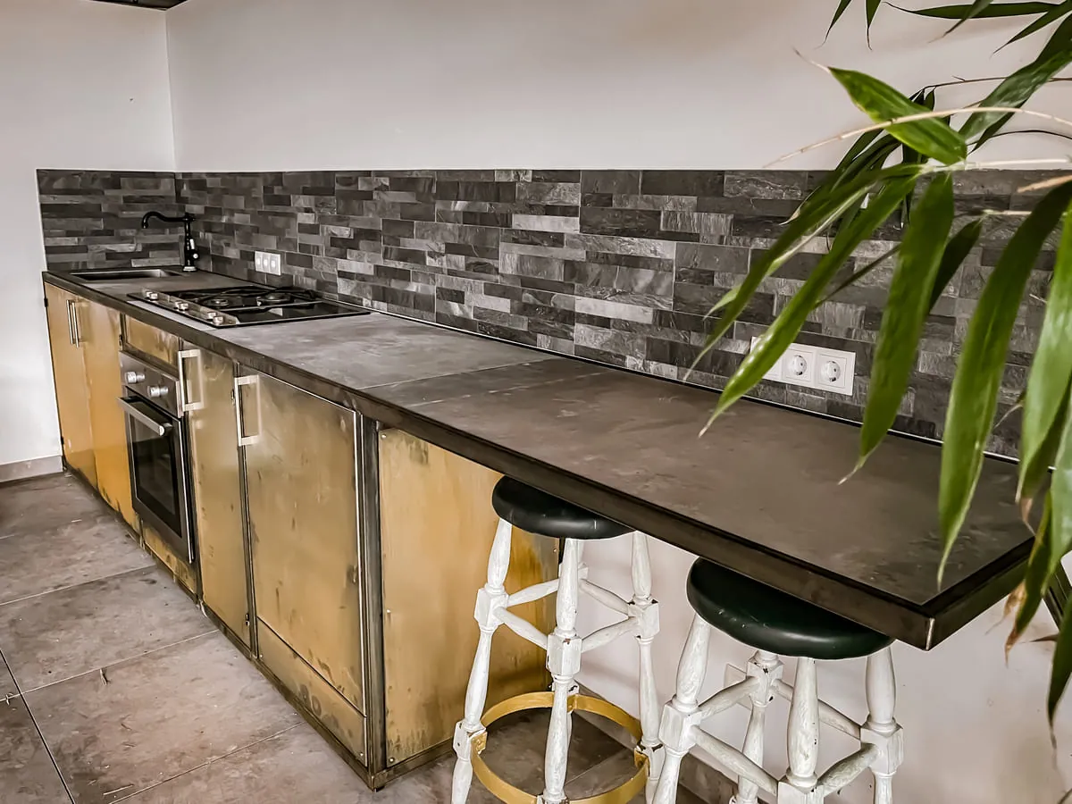 Küche im Industrial-Stil mit Stahl-Arbeitsplatte und Messing-Fronten