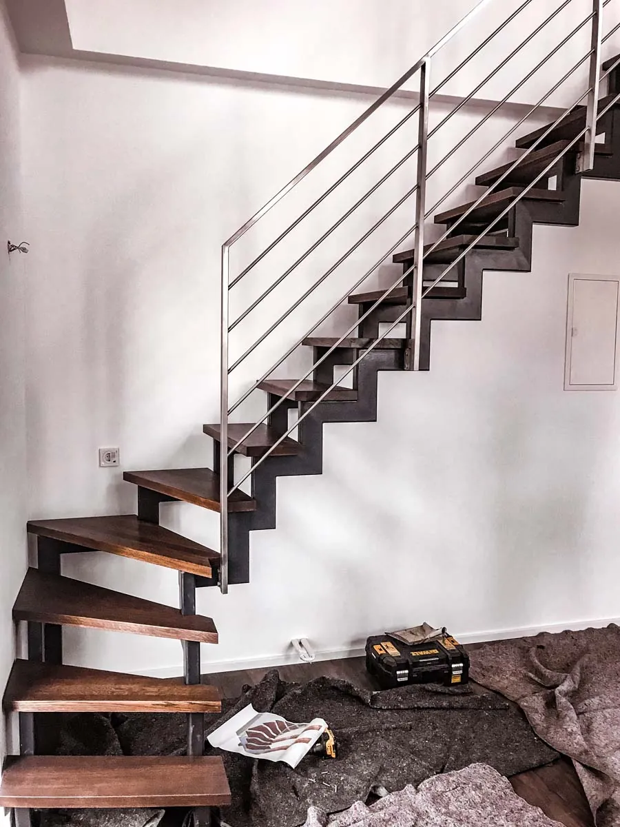 Innentreppe aus Stahl mit dunklen Holzstufen und Edelstahlgeländer